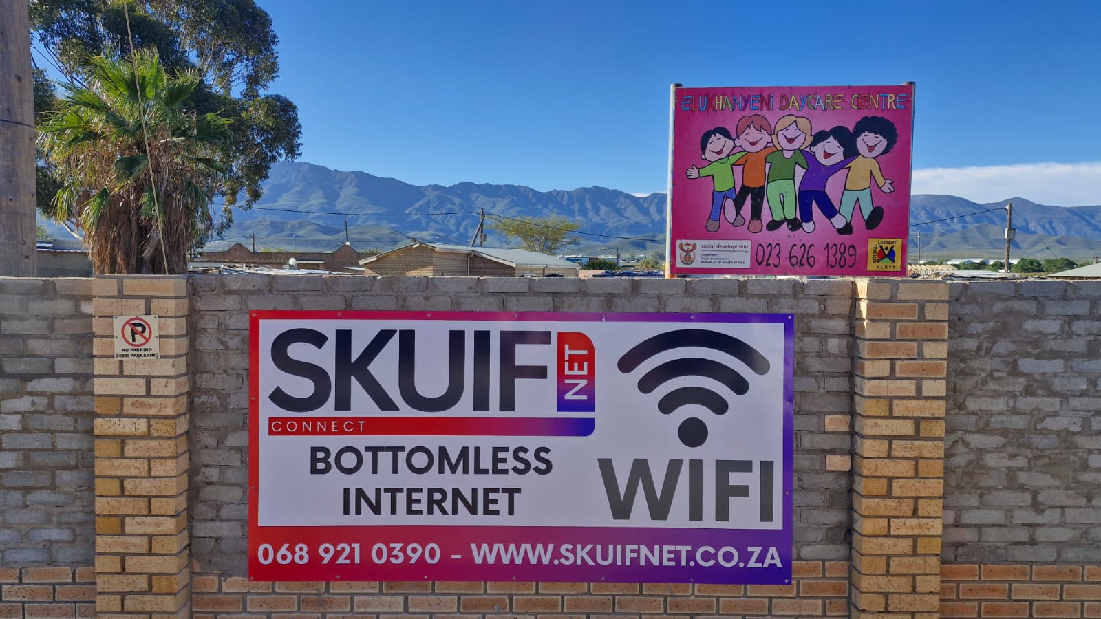 SkuifNet banner beside a local community centre with valley mountains behind